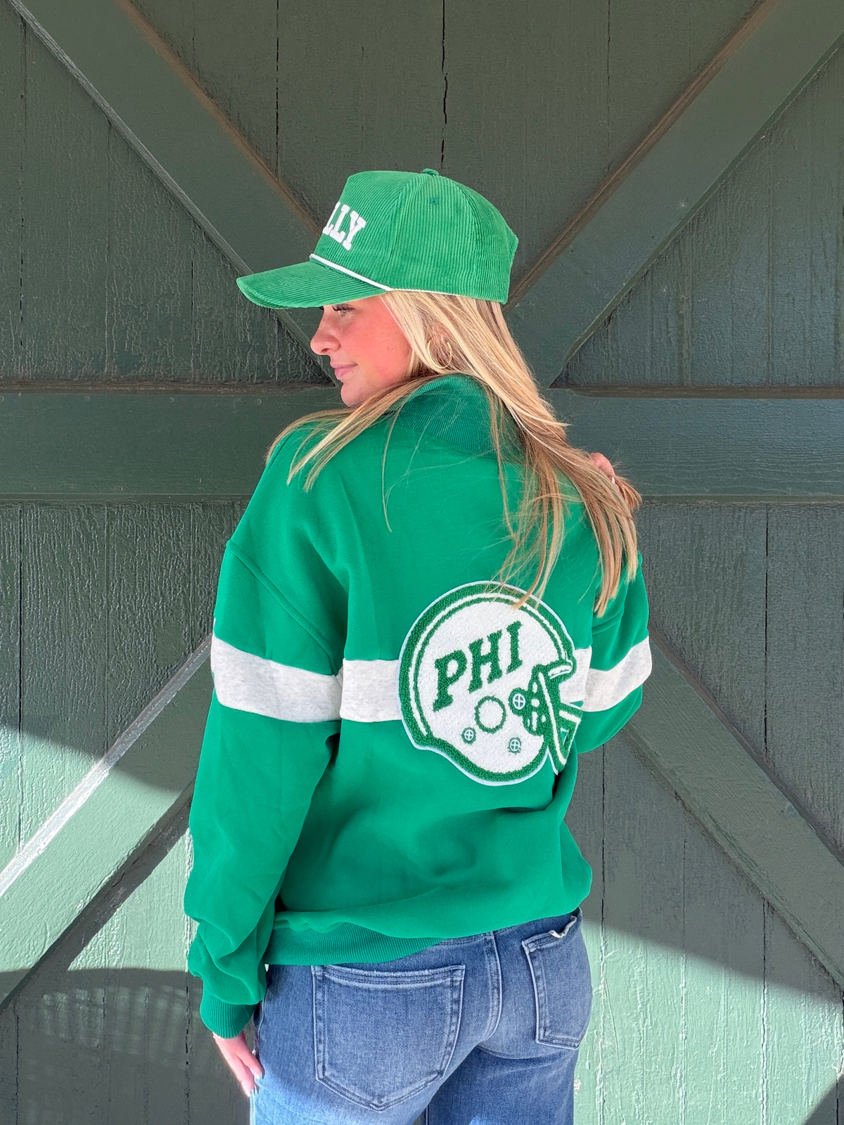 Green quarter-zip sweatshirt with white stripe and circular Philadelphia logo