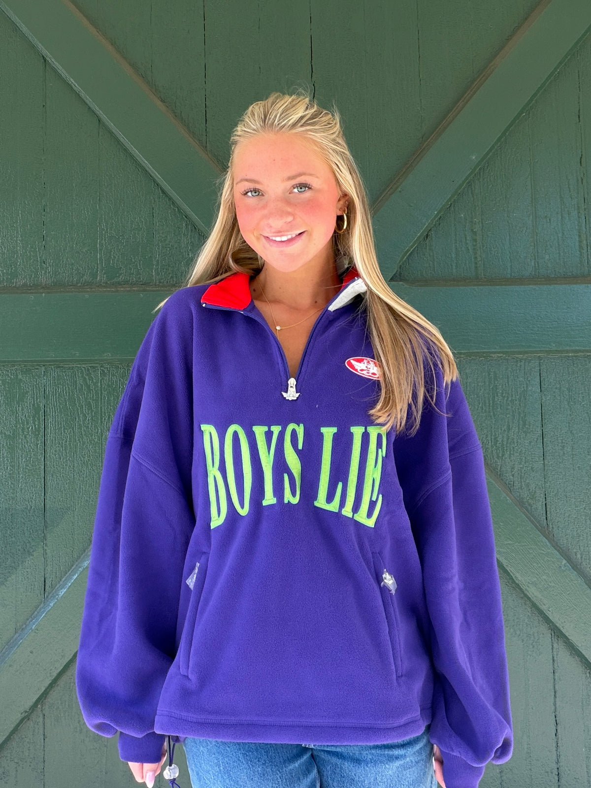 Purple half-zip sweatshirt with 'BOYS LIE' chest graphic and red collar lining