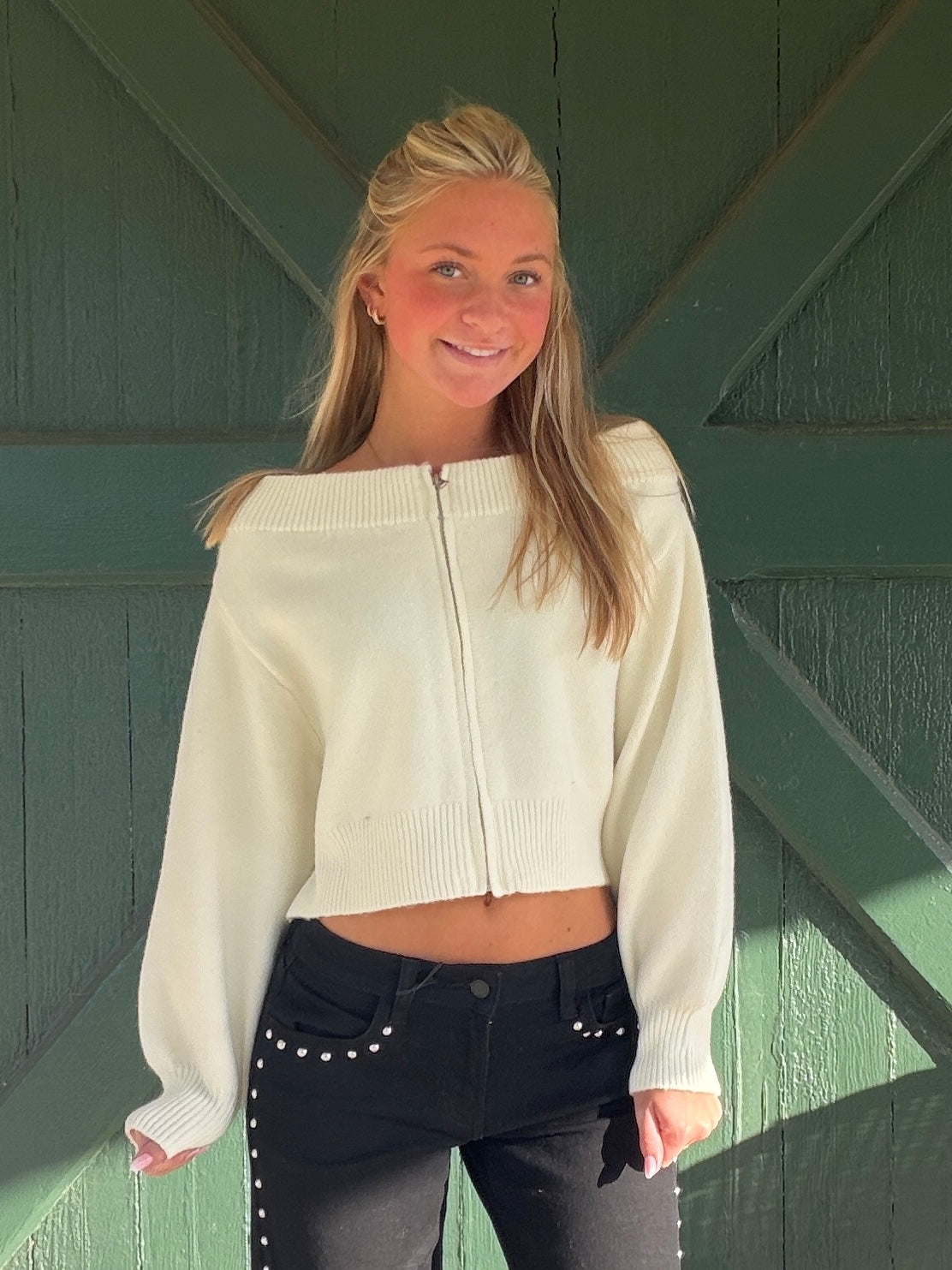 Cream zip-front off-the-shoulder sweater with visible zipper and ribbed collar, long sleeves
