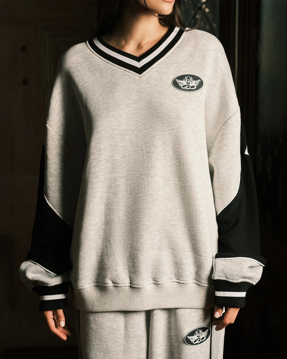 Boys grey V-neck sweatshirt with small chest badge and black-striped cuffs