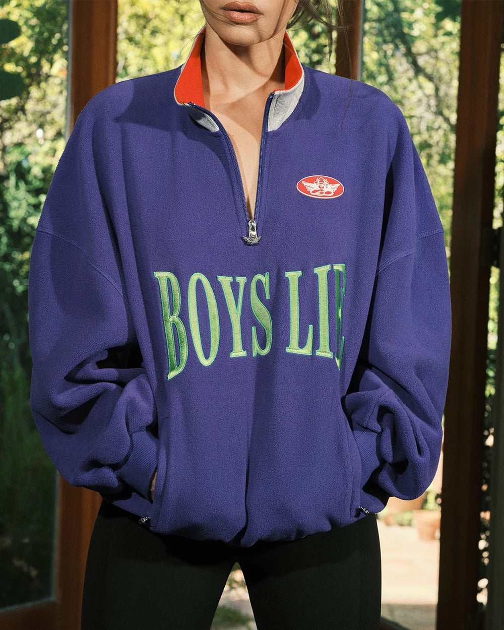 Purple quarter-zip sweatshirt, 'BOYS LIE' graphic with red zip lining in close view
