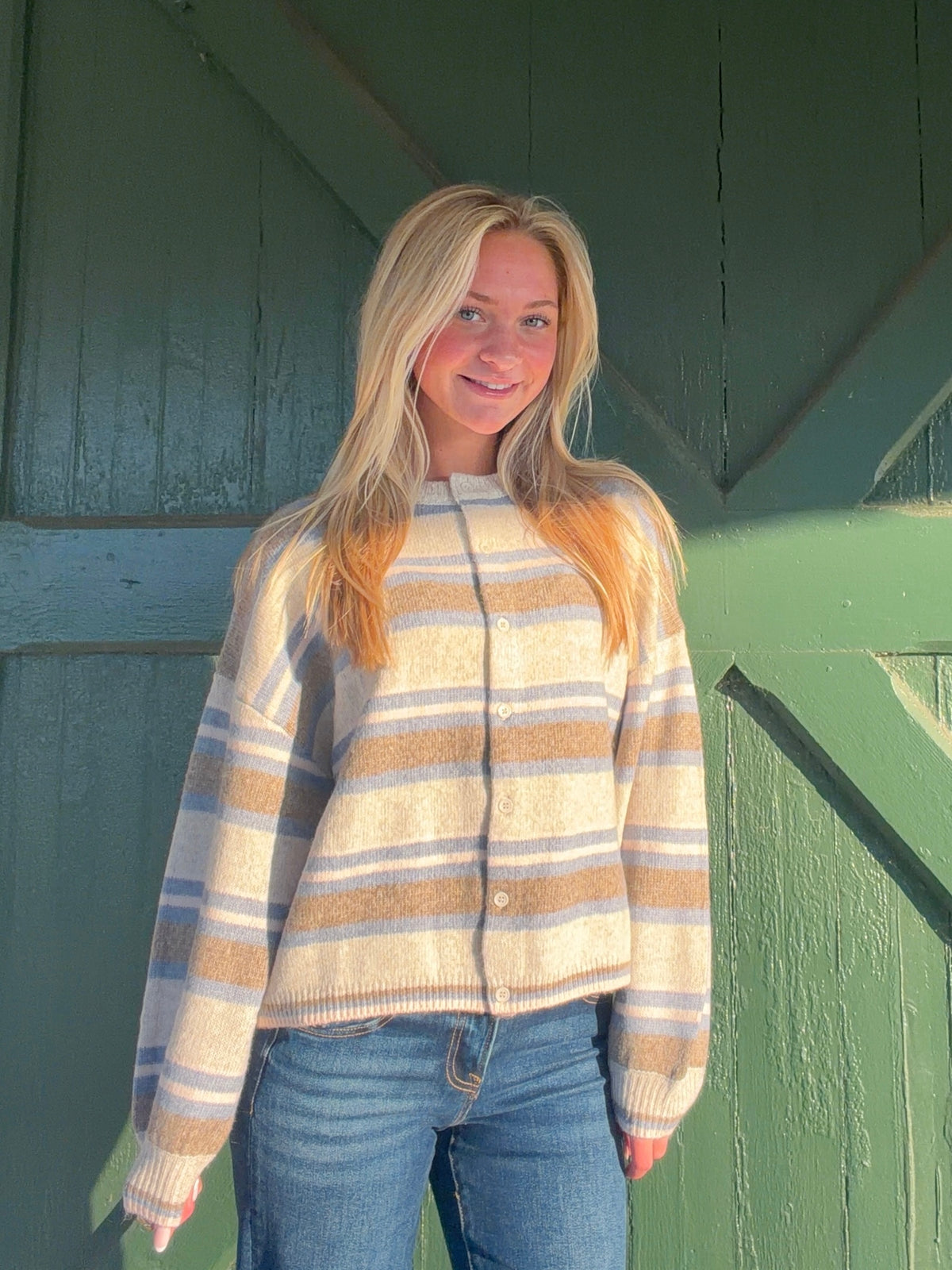 Beige cardigan with blue and tan horizontal stripes, button front, and ribbed edges
