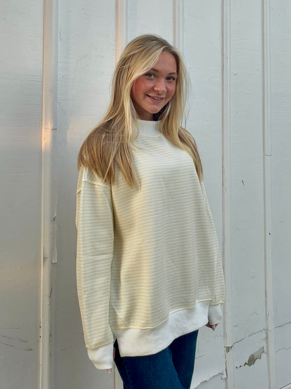 Yellow and white striped mockneck sweatshirt shown at an angle, with ribbed cuffs