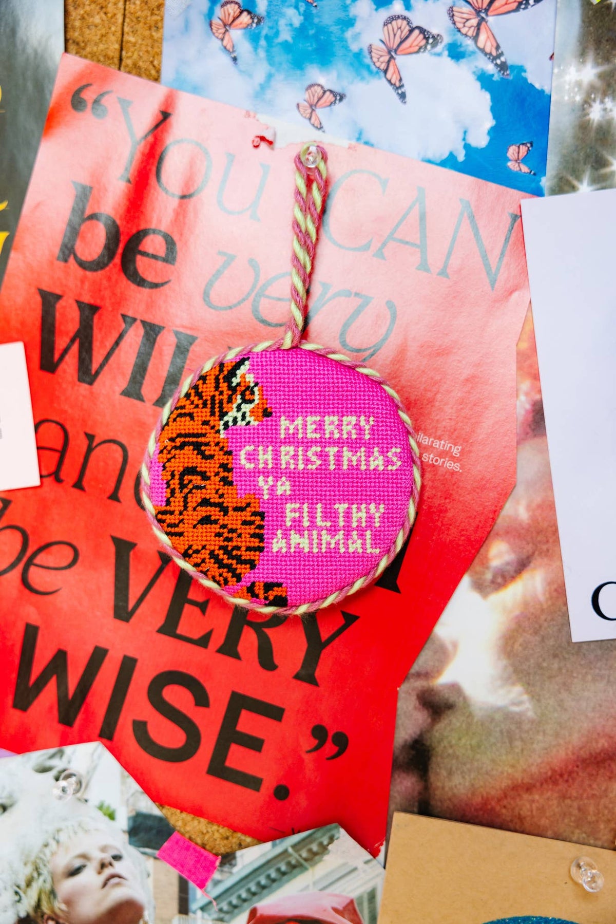 Needlepoint Christmas ornament ball with twine top, stitched “MERRY CHRISTMAS FILTHY ANIMAL”