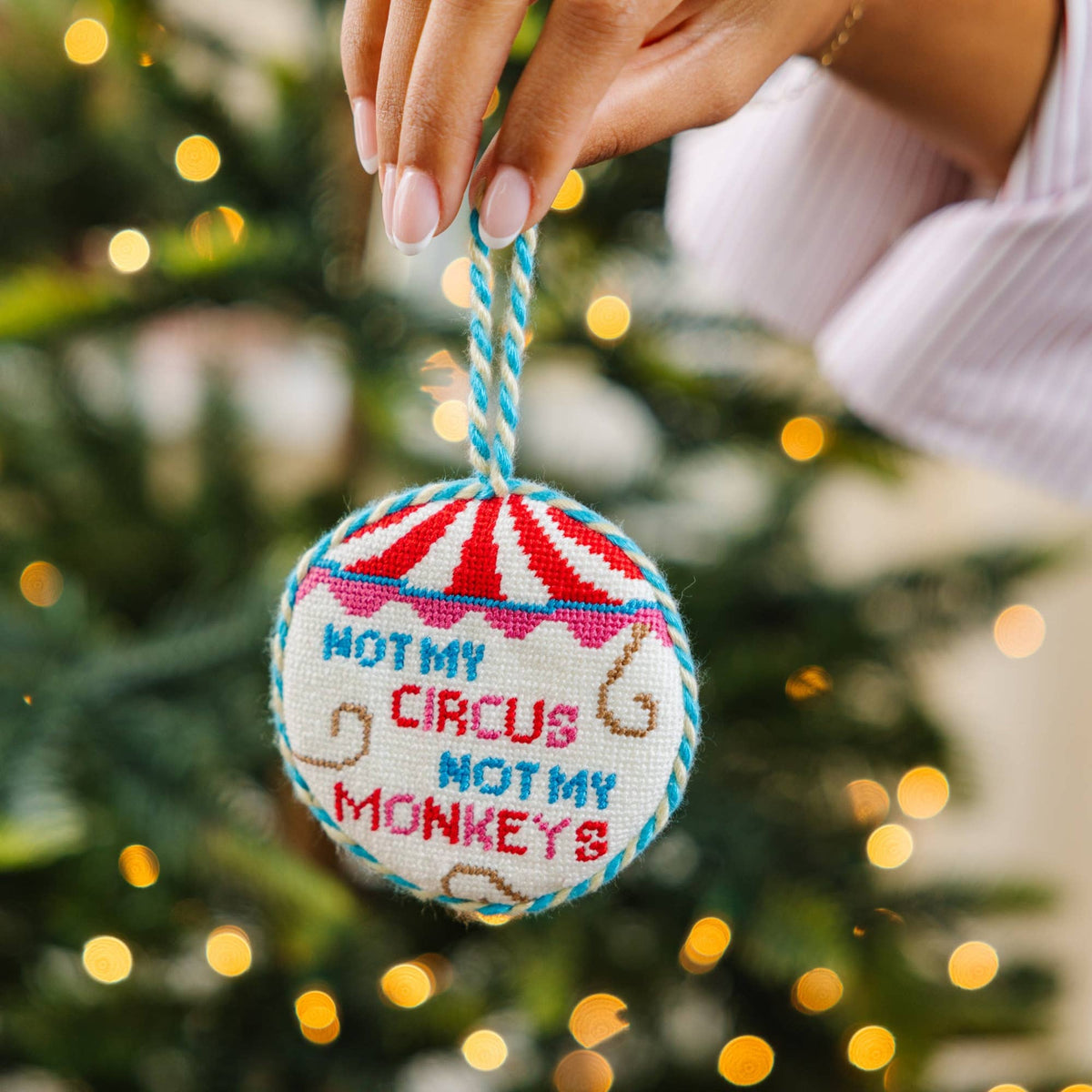 Round needlepoint ornament by Furbish Studio on cord, multicolor circus lettering