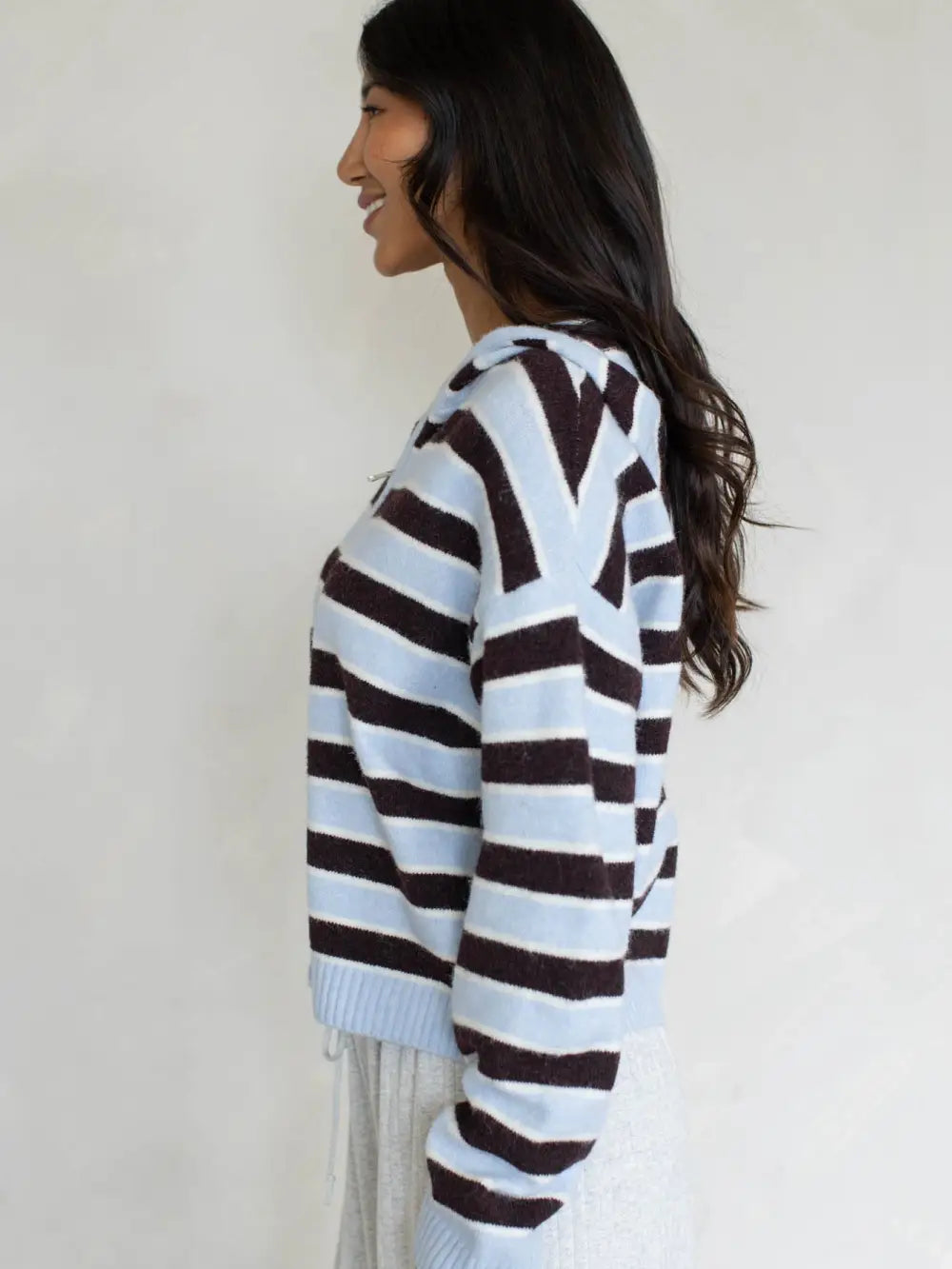 Multi-stripe zip sweater hoodie with hood, side view, light-and-dark stripes.