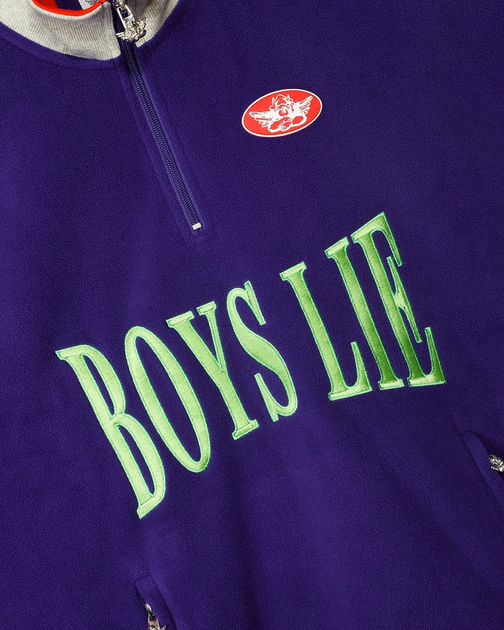 Purple zip sweatshirt close-up, green 'BOYS LIE' lettering with small chest patch