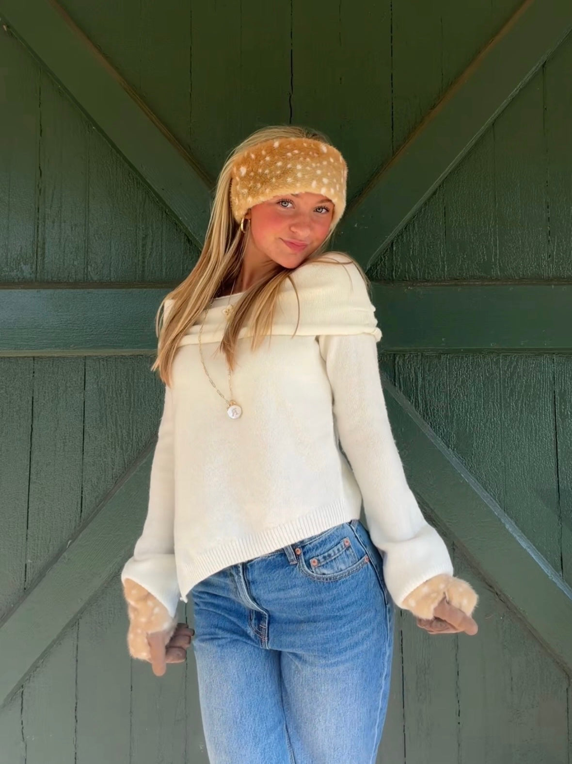 Model wearing the ivory Audrey knit sweater with a wide folded neckline and flared sleeves, styled with jeans.