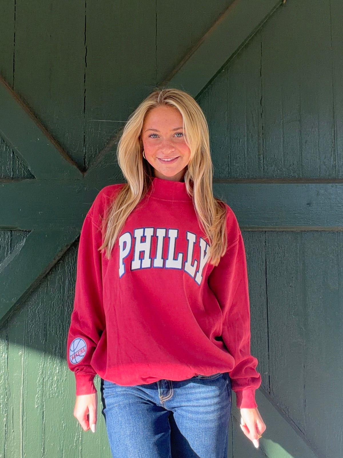 Red mock-neck sweatshirt with large PHILLY lettering and a 76ers sleeve patch