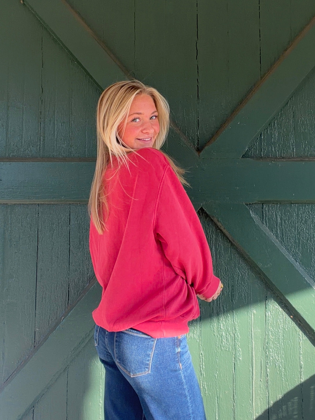 Back of a red mock-neck sweatshirt with a plain design and ribbed hem