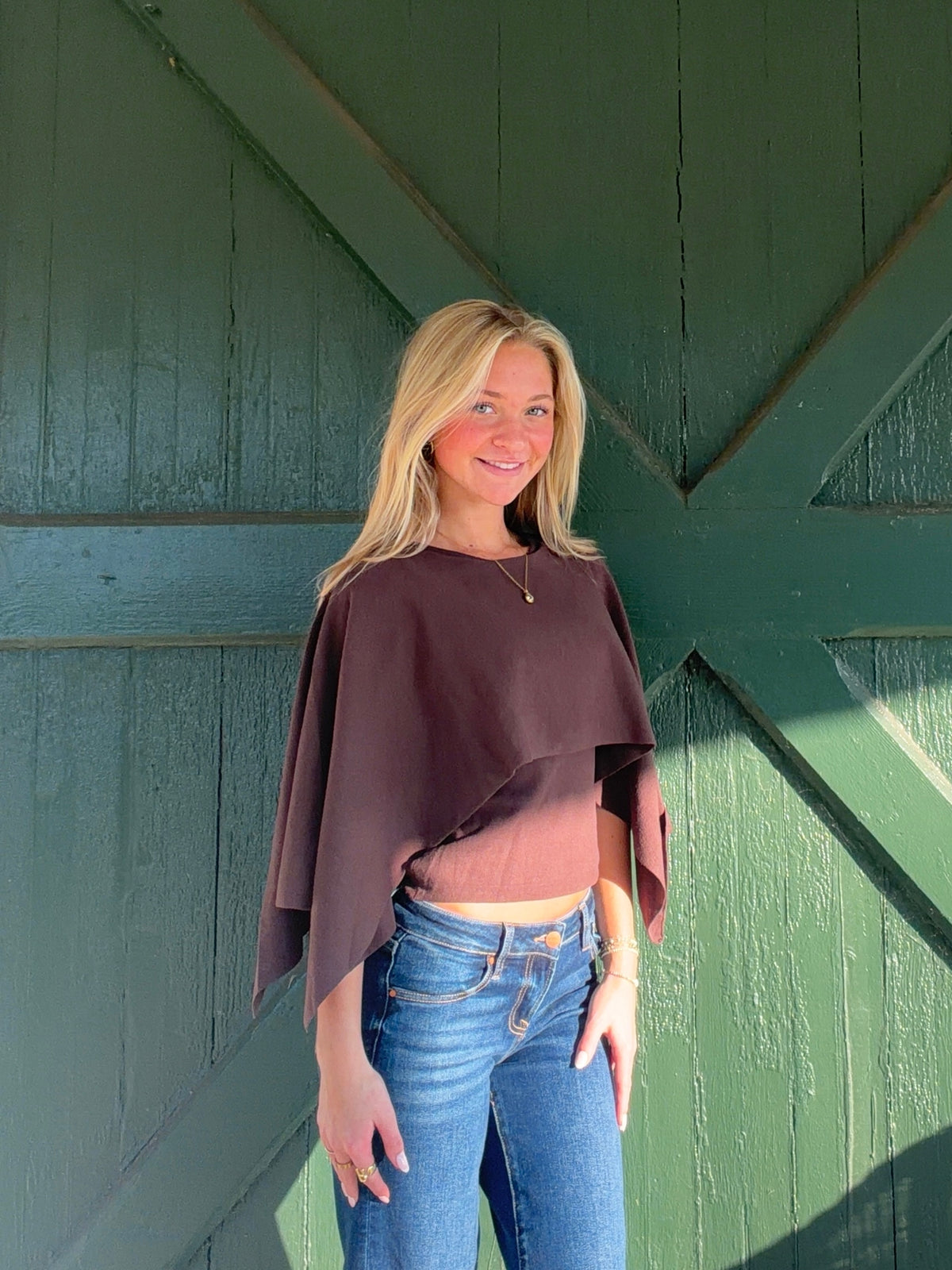 Brown cropped cape sweater with a layered front and flowing, asymmetrical sleeves