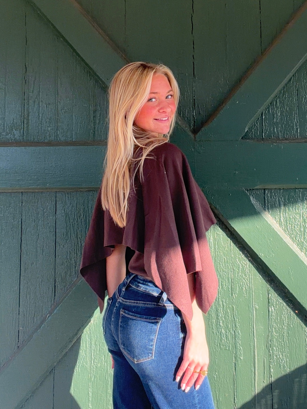 Brown cape sweater shown from the side and back, with a loose draped silhouette