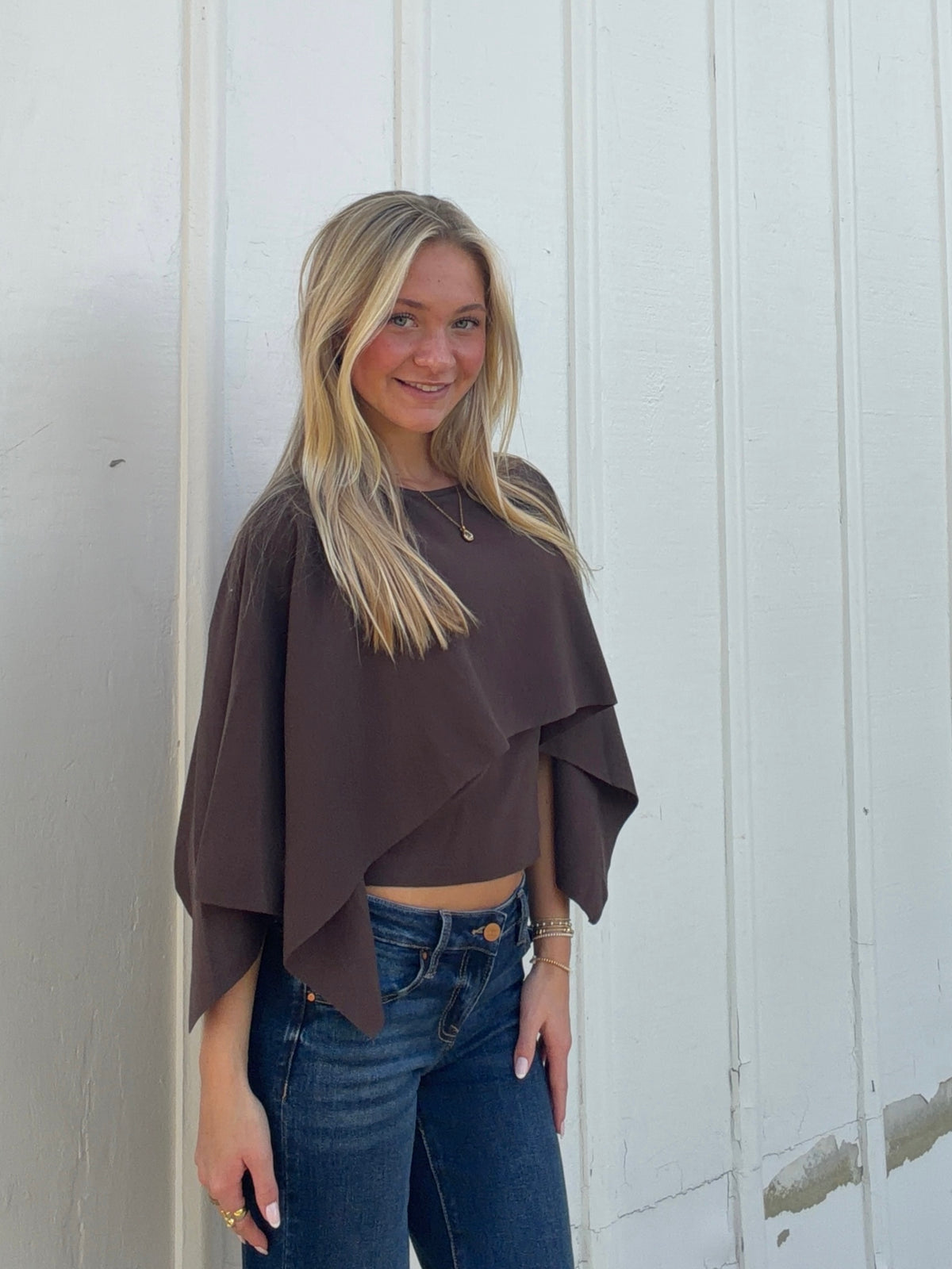 Brown cape sweater in a three-quarter view, showing its flowing front and side drape