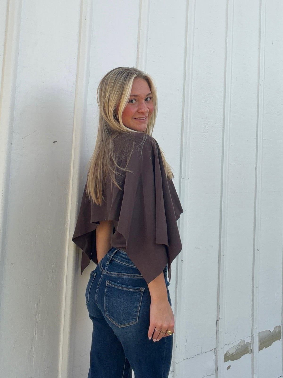 Brown cape sweater from the back, showing its loose fit and layered sleeve panels
