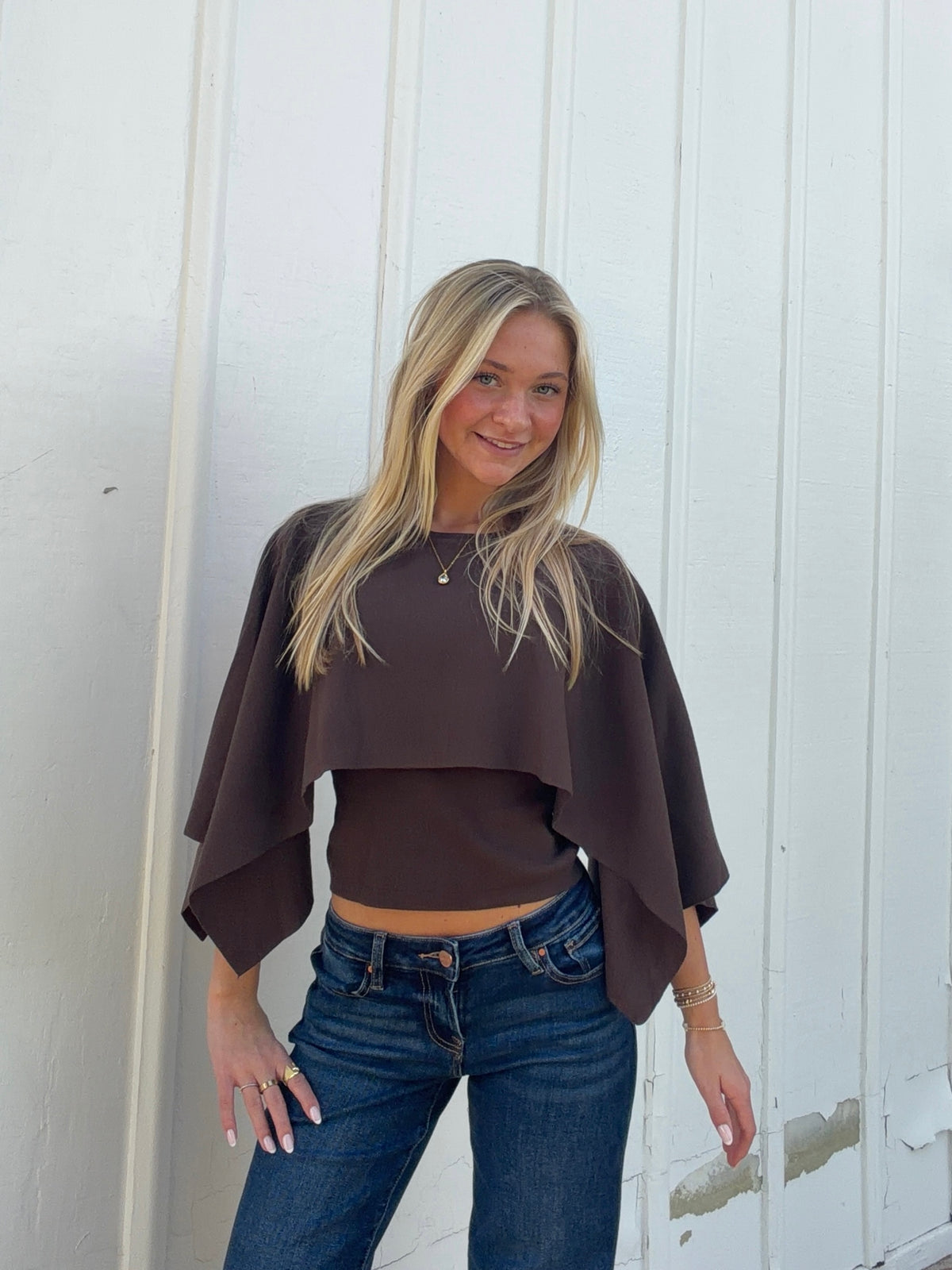 Brown cape sweater with a layered front and wide, pointed sleeve panels