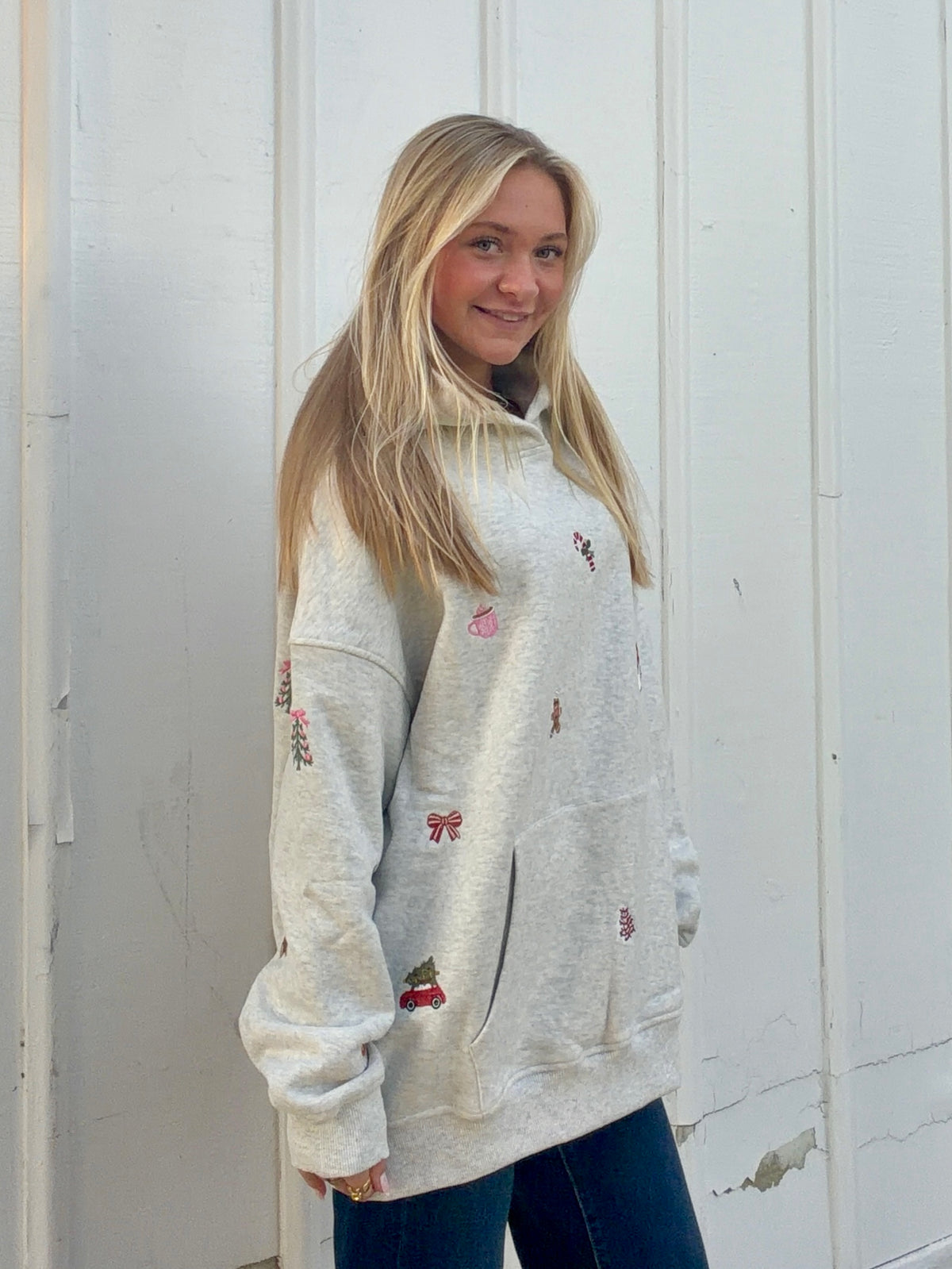 Oatmeal hoodie with small Christmas symbols embroidered across the front and sleeves