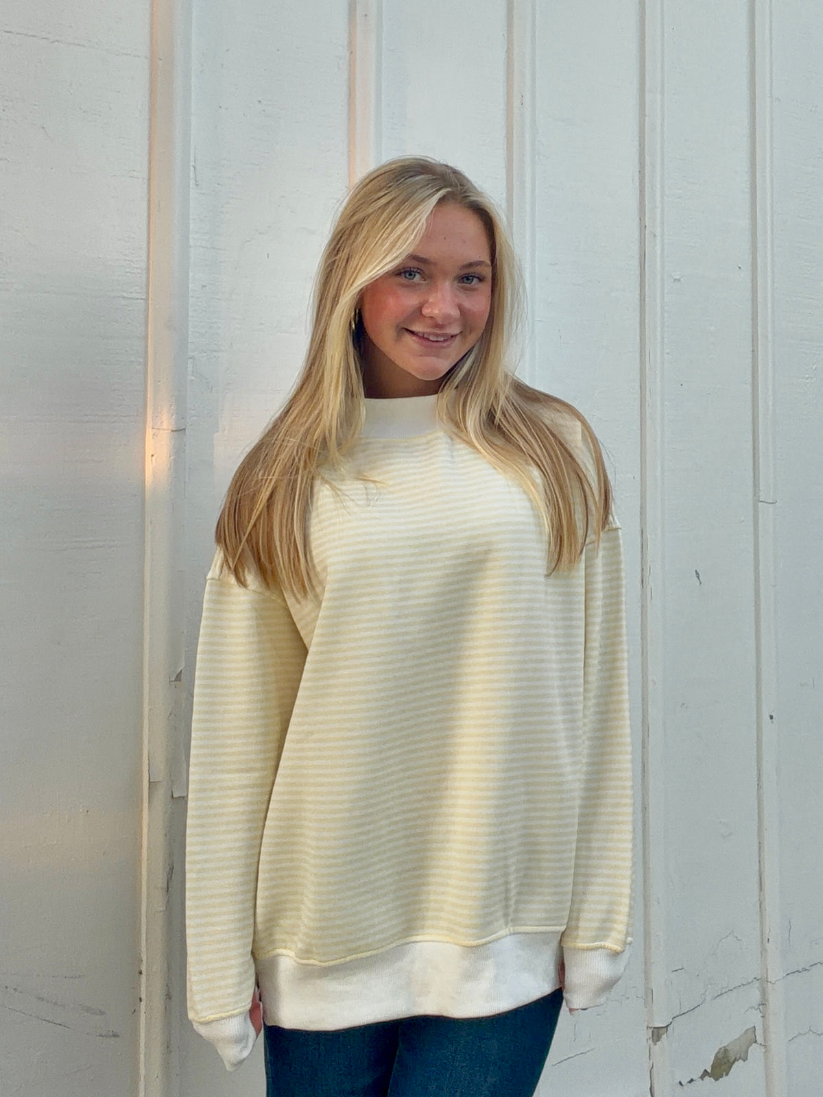 Yellow and white striped mockneck sweatshirt with long sleeves and a white hem