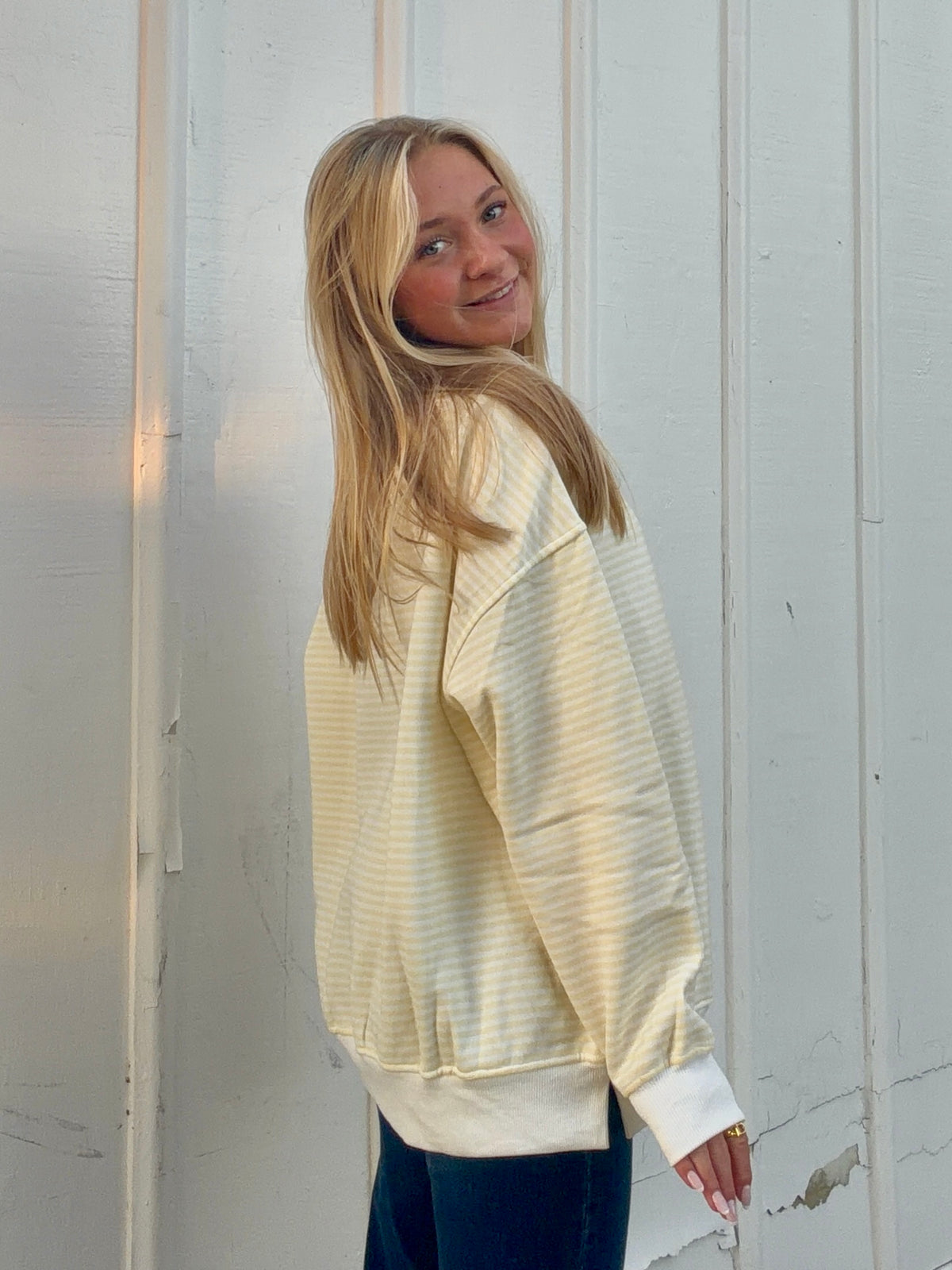 Back and side view of a yellow and white striped sweatshirt with a mockneck